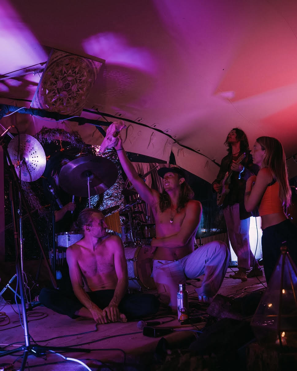Band gathered on stage around a skull held aloft under purple light