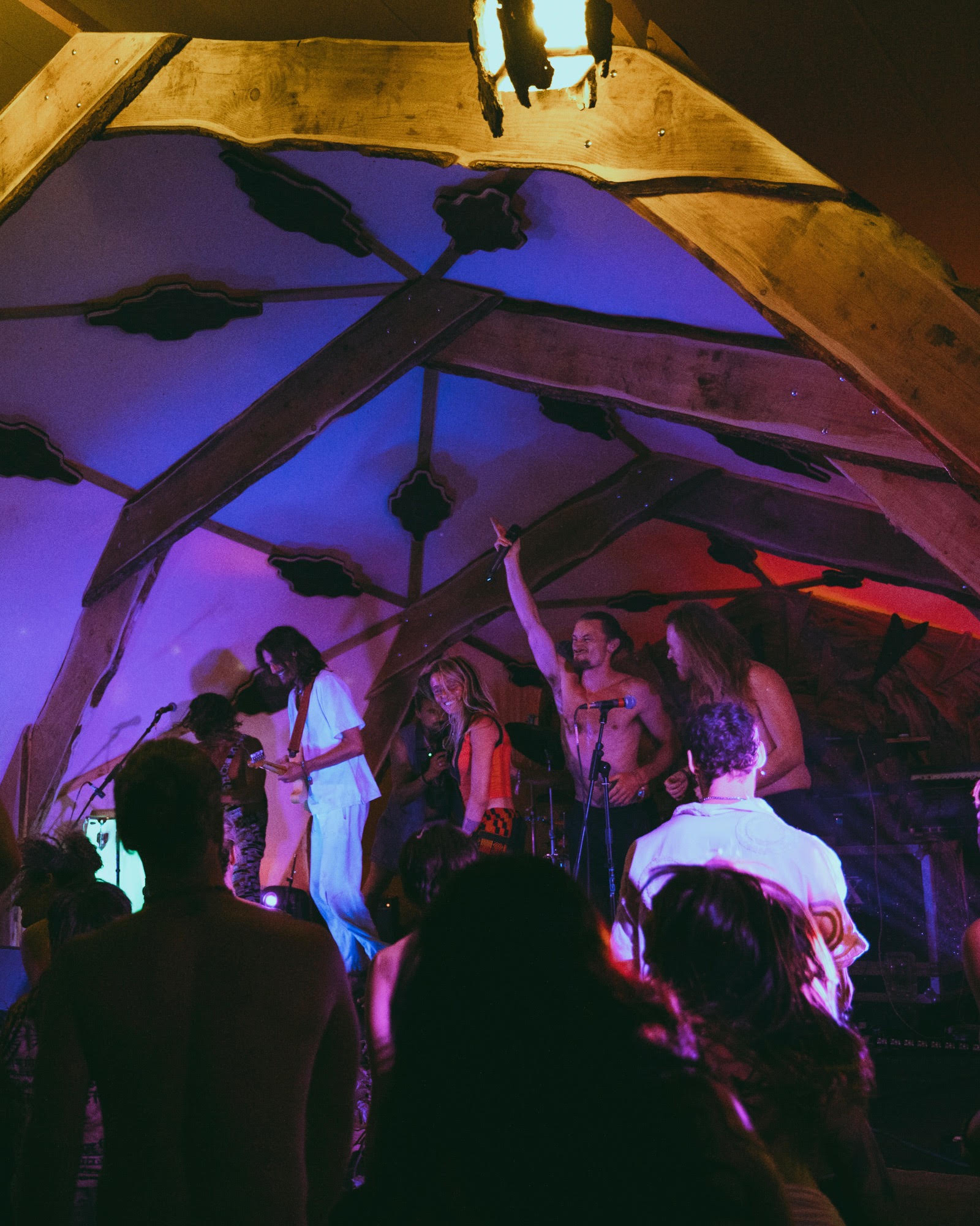 Band performing on a wooden geodesic stage, crowd in front