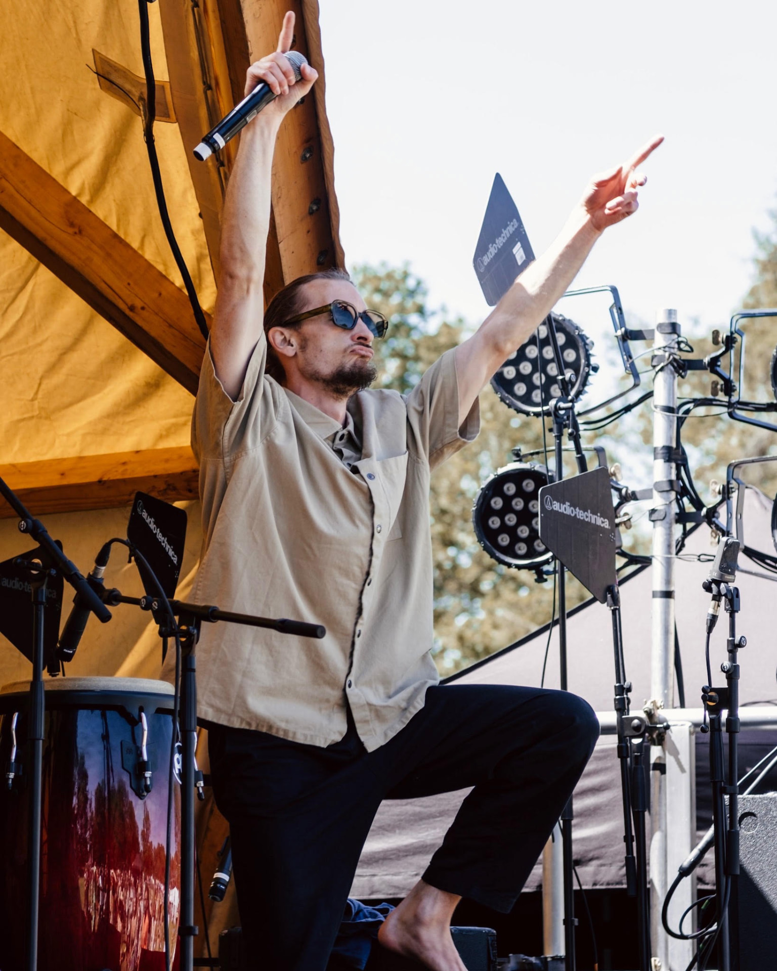 MC with arms raised holding a mic on the outdoor stage